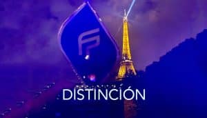 Un trofeo azul con un logotipo "F" estilizado se sostiene frente a la Torre Eiffel iluminada por la noche. La palabra "Distinción" aparece de manera destacada en la imagen en texto blanco, celebrando el mayor crecimiento de Fountaine Pajot. El fondo es oscuro con tonalidades violetas azuladas.
